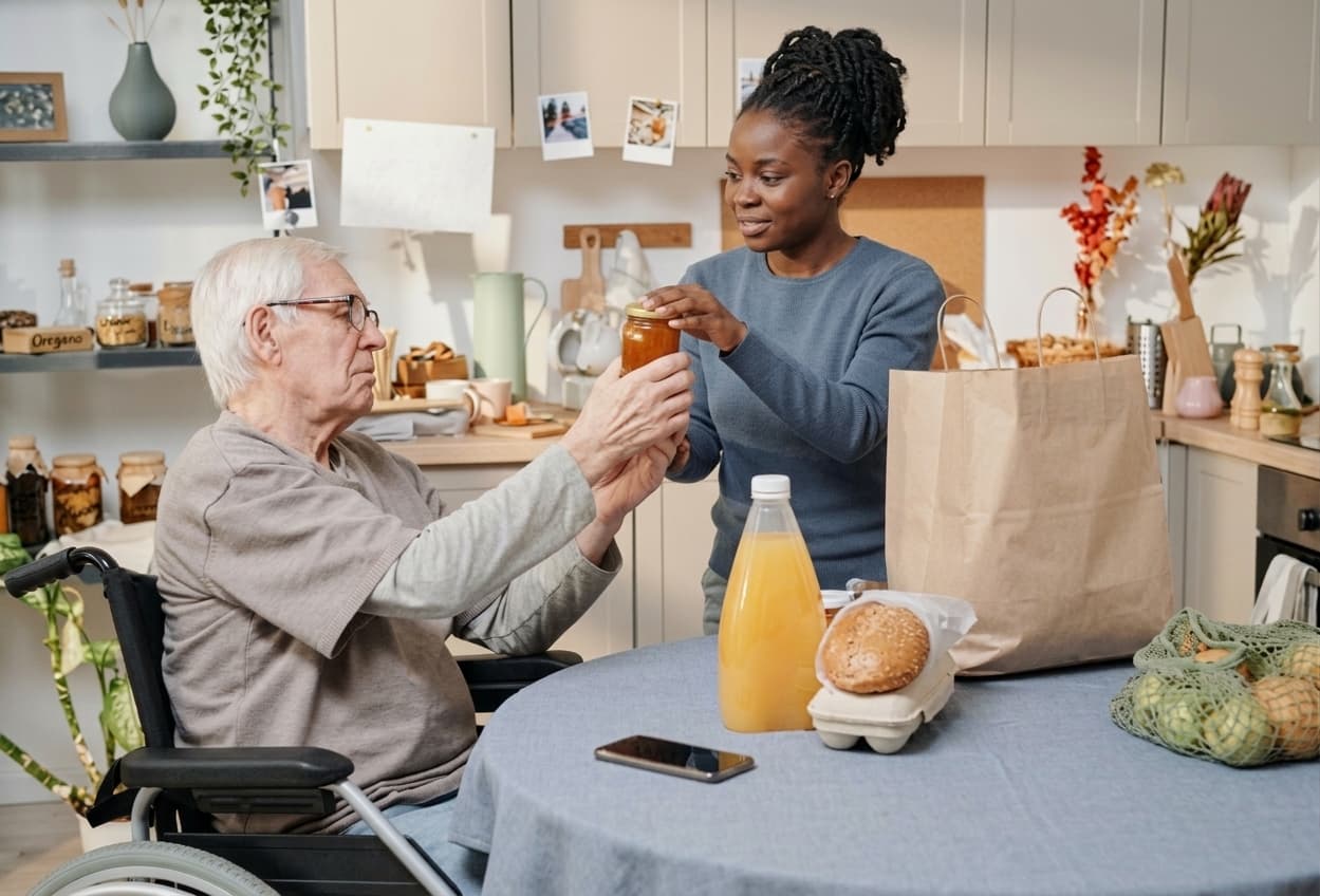 A ProxyKare caregiver helping a client with groceries in the kitchen.